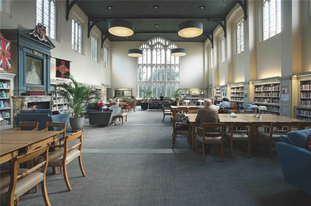 Cheltenham College – Weitläufige historische Bibliothek mit hohen Bogenfenstern und Lesebereichen
