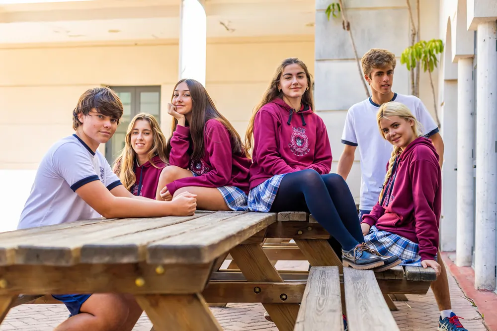 Sage College – Gruppe von Schülern in Schuluniform sitzt zusammen im Freien