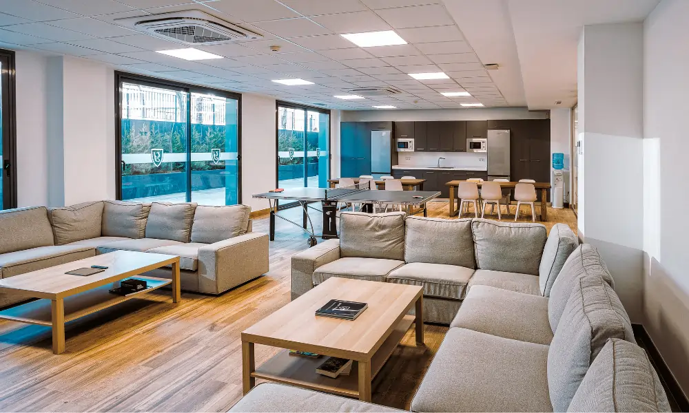 Yago School Sevilla – Heller Gemeinschaftsraum mit Lounge-Bereich und Küchenzeile