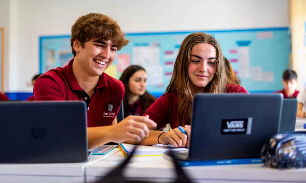 Sage College – Zwei Schüler arbeiten lachend gemeinsam am Laptop im Unterricht