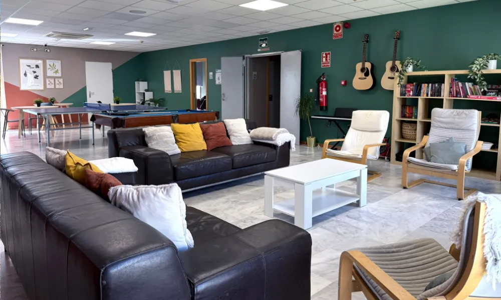 Sage College – Einladender Aufenthaltsraum mit Sofas, Gitarren und Bücherregal